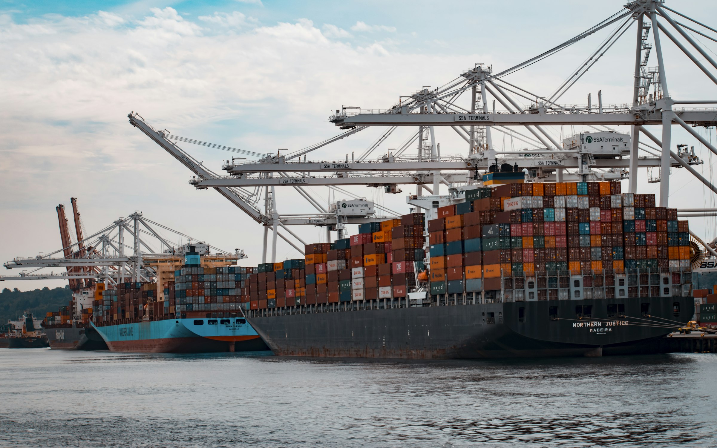 Container ships alongside a terminal berth, gantry cranes working the stacks.